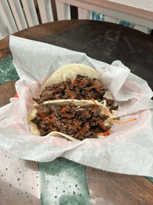 a taco is wrapped in wax paper and sitting on a wooden table