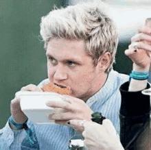 a man is eating a sandwich from a white bowl .