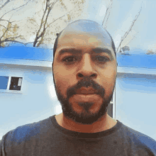 a man with a beard is standing in front of a blue house