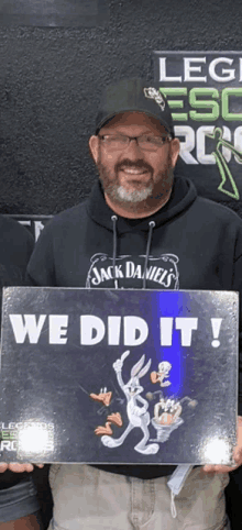 a man in a jack daniels hoodie holds up a sign that says we did it