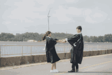 a man and a woman in graduation gowns hold hands