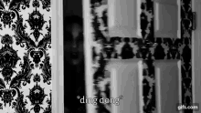 a black and white photo of a person behind a door with the words " ding dong " written on it