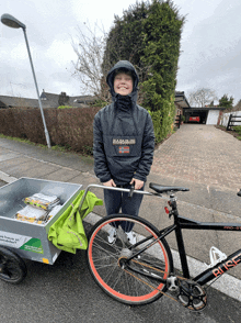 a boy wearing a napapijri jacket stands next to a bike