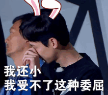 a man wearing bunny ears covers his face with his hand