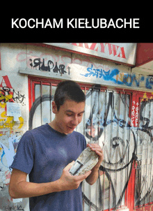 a young man is standing in front of a graffiti covered wall with the words kocham kielubache on the bottom