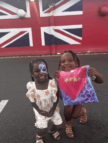 two little girls are posing for a picture in front of a large british flag