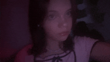 a young girl is taking a selfie in a dark room with a red light behind her .