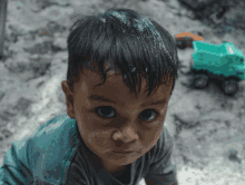 a young boy with a green toy truck in the background