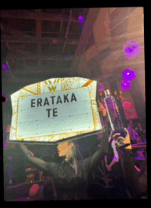 a woman is holding a sign that says " erataka te "