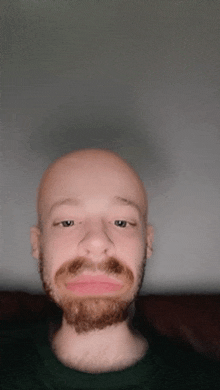 a bald man with a beard is making a face