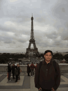 a man is standing in front of the eiffel tower