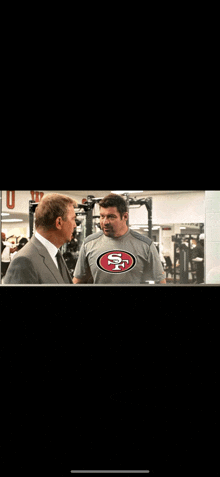 a man wearing a san francisco 49ers shirt is talking to another man