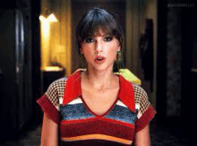 a woman in a striped sweater is making a funny face in a room .