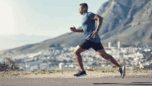 a man in a blue shirt and black shorts is running on a road .