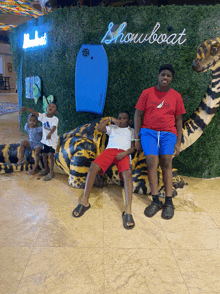 a group of young boys are sitting on a stuffed animal in front of a wall that says showboat