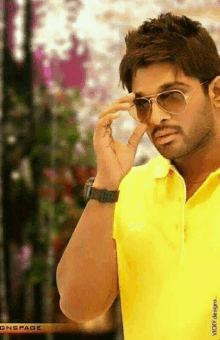 a man in a yellow shirt is wearing sunglasses and a watch .