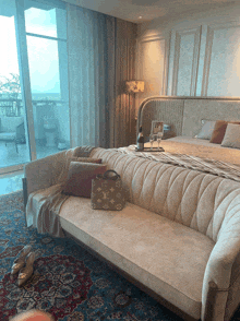 a bedroom with a couch and a louis vuitton bag