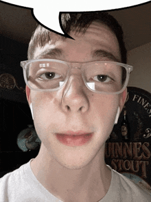 a young man wearing glasses stands in front of a sign that says " guinness stout "