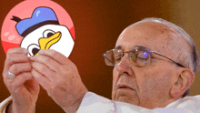 a man wearing glasses is holding a picture of a duck with a blue hat