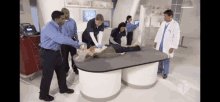 a group of doctors and nurses are standing around a table with a man laying on it