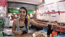 a woman is sitting at a table with a plate of food in front of a sign that says daily sub