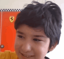 a young boy with a ponytail is smiling in front of a ferrari poster .