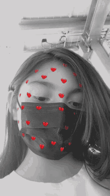 a girl wearing a black face mask with hearts on her face