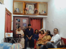 a group of people sit on a couch in front of a picture of jesus on the wall