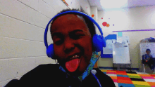 a boy wearing blue headphones sticks out his tongue in a classroom