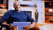 michael jordan is smiling while looking at his tablet