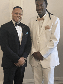 two men in tuxedos and bow ties pose for a photo