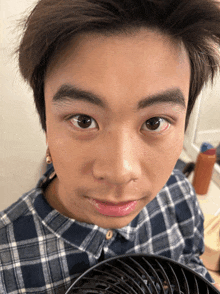 a close up of a person 's face with a fan in front of them