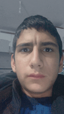 a close up of a young man 's face with a ceiling fan in the background