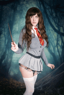 a woman in a school uniform holds a wand