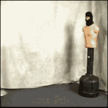 a mannequin wearing a black mask is standing next to a punching bag