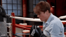 a young man is sitting in a boxing ring wearing boxing gloves .