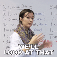 a woman stands in front of a white board with the words " we 'll look at that " written on it