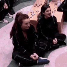 two women are sitting on the floor with their legs crossed