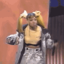 a woman is dancing on a stage wearing a yellow top and a jacket .