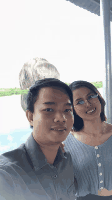 a man and a woman posing for a picture with a large rock in the background