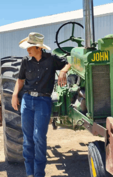 a man in a cowboy hat leans against a john deere tractor