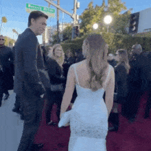 a man and a woman are standing next to each other on a red carpet . the woman is wearing a white dress .