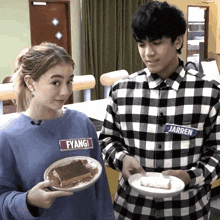 a girl wearing a blue fyangi sweatshirt holds a plate of food next to a boy in a plaid shirt