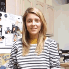 a woman in a striped shirt is standing in front of a refrigerator with a sign that says save water