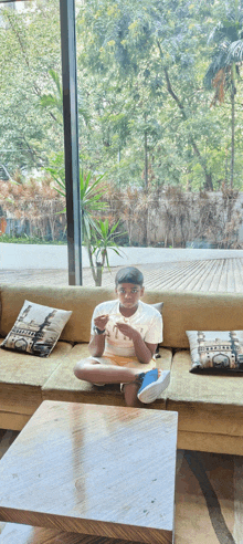 a young boy is sitting on a couch with his legs crossed