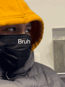 a person wearing a yellow hoodie and a black face mask that says bruh