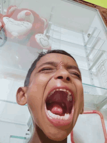 a young boy is making a funny face in front of a teddy bear with a heart on it