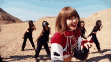 a group of women are dancing in the desert and one of them is wearing a red and white sweater with the letter a on it