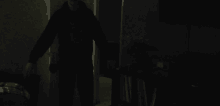 a man in a black hoodie is standing in the dark in a dark room .