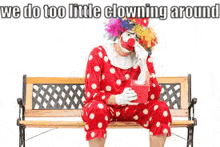 a clown is sitting on a bench with a box in his hand and crying .